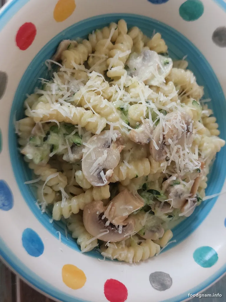 piatto di pasta zucchine, funghi e crema di latte con formaggio grattugiato